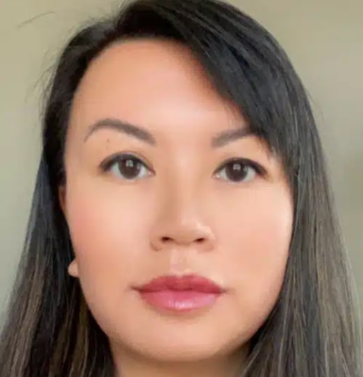 Professional headshot of woman with long dark hair in neutral indoor setting for dental practice.