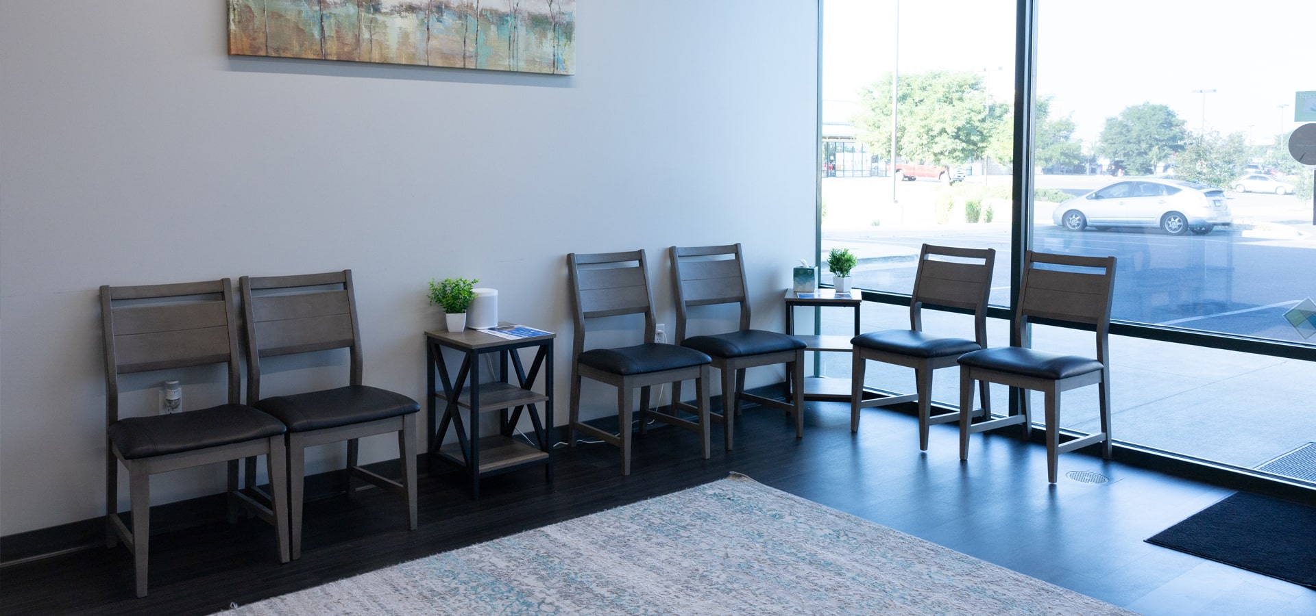 Modern dental waiting room with comfortable seating, large windows, and contemporary décor.