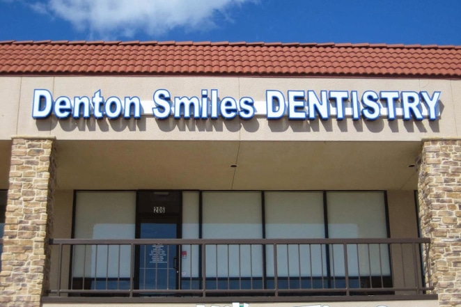 Denton Smiles Dentistry storefront with stone facade, signage, and balcony railing.