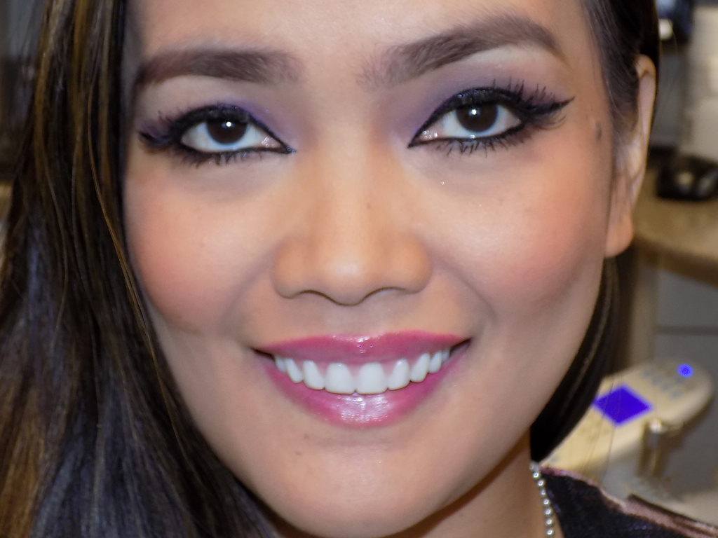 Woman smiling at camera, displaying bright white teeth in dental office setting.